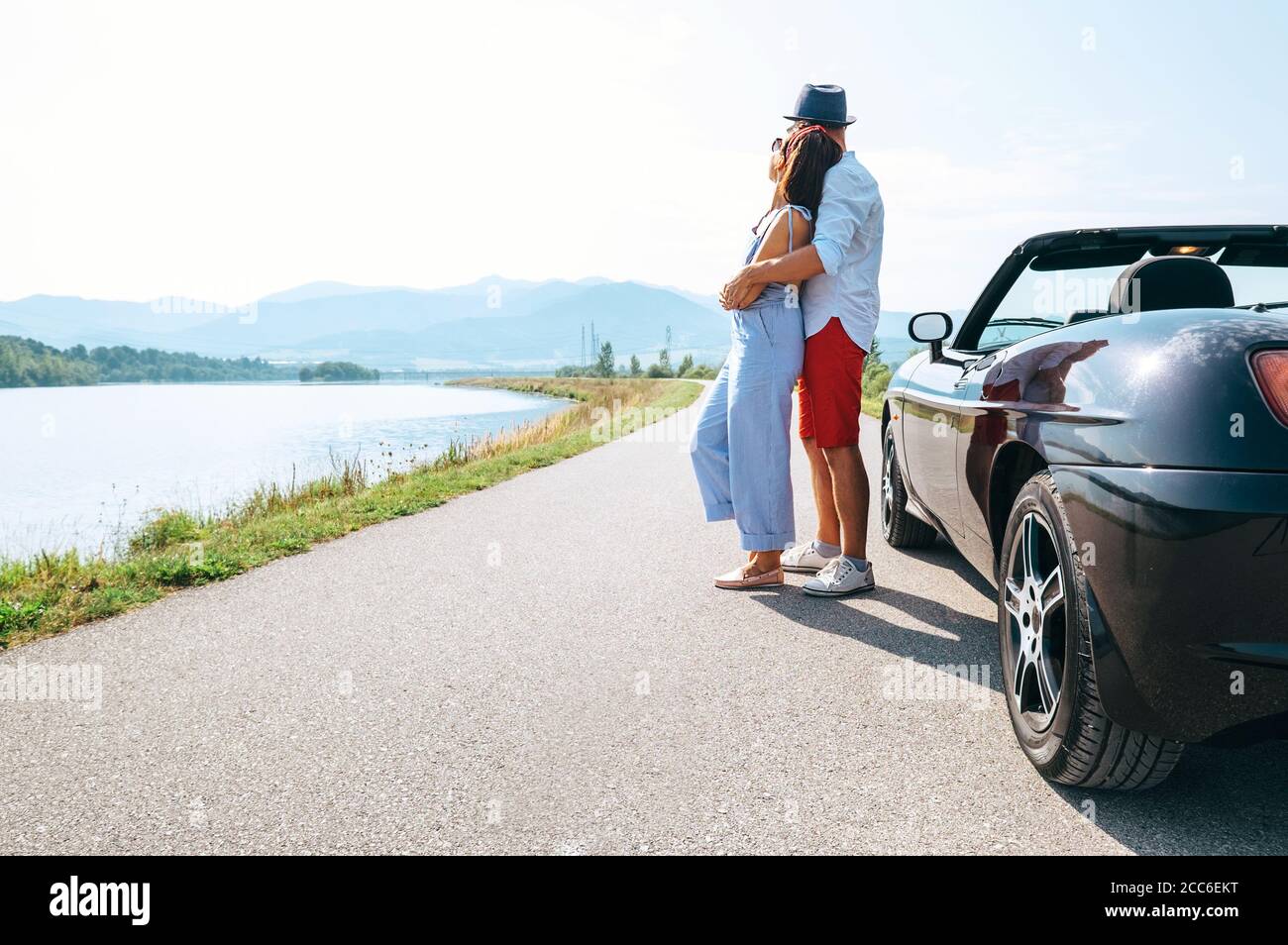 Un couple amoureux se tient près de la voiture cabriolet la route pittoresque de montagne Banque D'Images