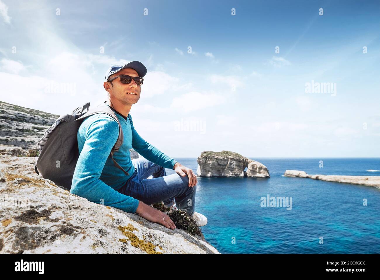 Homme avec sac à dos assis sur la côte rocheuse Banque D'Images