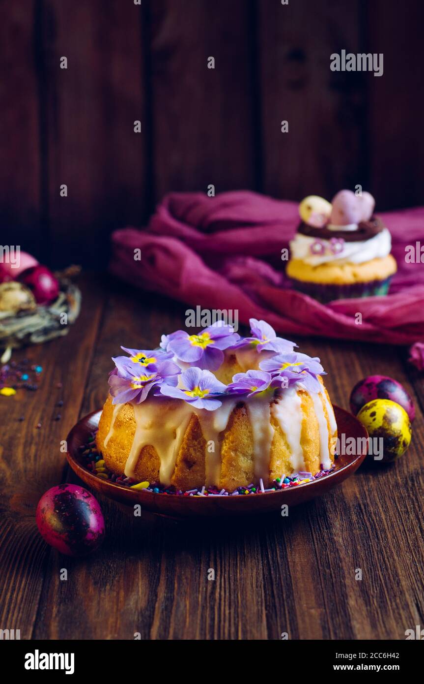 Gâteau traditionnel de Pâques décoré de fleurs de primrose et d'œufs peints en nid naturel Banque D'Images