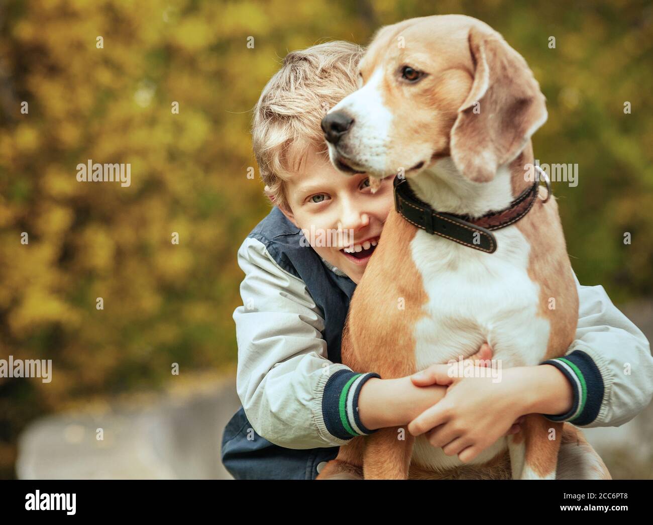 Un garçon souriant enlègue son meilleur ami beagle chien Banque D'Images