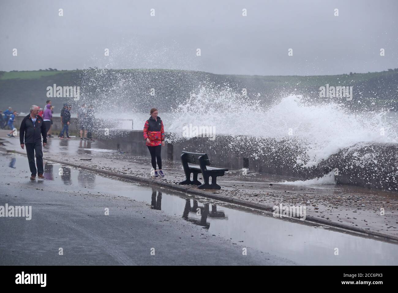 Les gens essaient d'éviter que les vagues ne s'écrasant sur le front Strand à Youghal, Co. Cork. Un avertissement de vent rouge a été émis par met Eireann pour la région, et un avertissement orange a été émis pour Galway, Mayo, Clare, Kerry, Limerick et Waterford, alors que Storm Ellen balaie le pays depuis mercredi soir. Banque D'Images