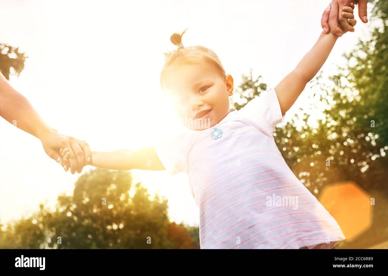 Petite fille de 2 ans marchant avec des parents tenant leur une image d'été éclatante pour les mains Banque D'Images