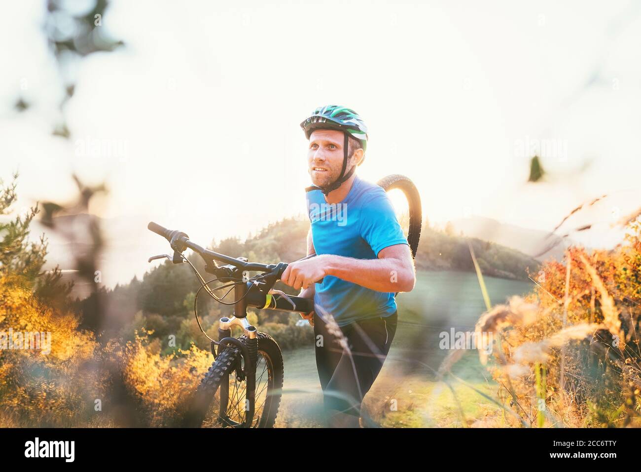 Membre de la compétition cyclo-cross, Man Mountain Biker, porte son vélo en haut de la colline Banque D'Images