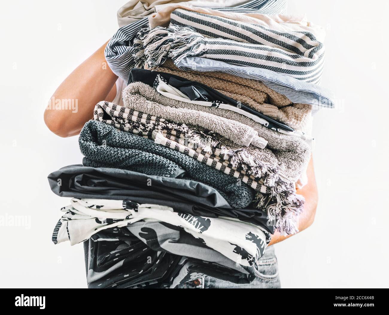 Grande pile de linge gris et beige en femme mains proches image vers le haut sur fond blanc Banque D'Images