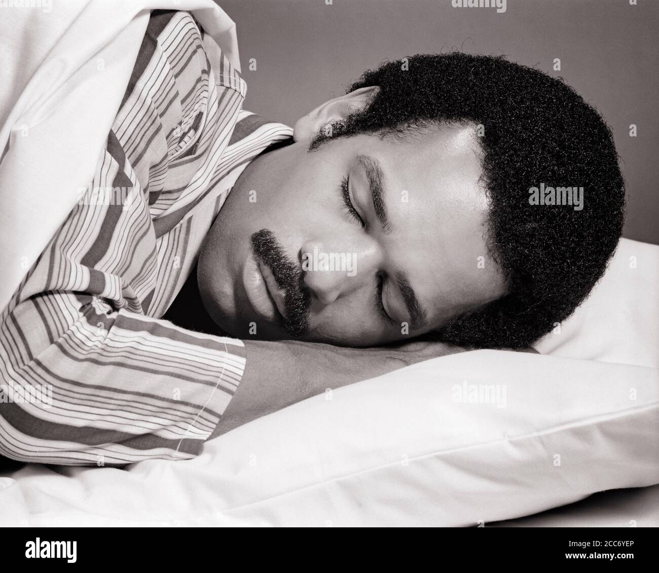 HOMME AFRO-AMÉRICAIN DES ANNÉES 1970 AVEC MOUSTACHE PORTANT UN PYJAMA À RAYURES ENDORMI AU LIT AVEC UNE EXPRESSION DU VISAGE PAISIBLE ET PAISIBLE - S20400 HAR001 HARS SERENITY EXPRESSIONS B&W REPOS MOUSTACHE RÊVES SOMMEIL TÊTE DE BIEN-ÊTRE ET LES ÉPAULES MOUSTACHES AFRO-AMÉRICAINS L'ETHNIE NOIRE AFRO-AMÉRICAINE DANS LE VISAGE D'OCCASION CHEVEUX PAISIBLE CONCEPT ÉCHAPPER ÉLÉGANT REPOSANT AGRÉABLE CROISSANCE DÉTENTE REPOS BIEN-ÊTRE JEUNE HOMME ADULTE NOIR ET BLANC HAR001 ANCIEN LES AFRO-AMÉRICAINS À LA MODE Banque D'Images