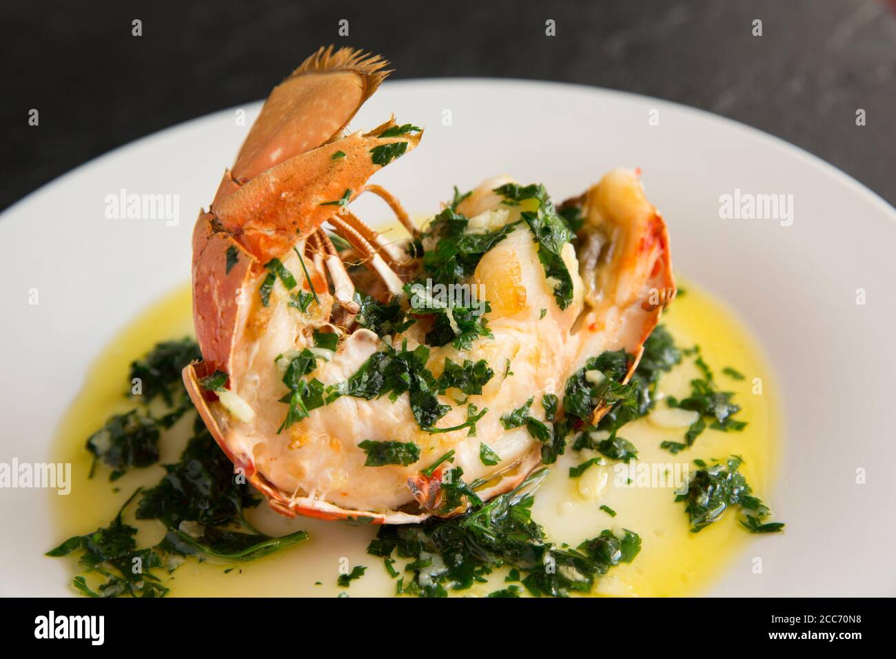 Une demi-queue de homard, Homarus gammarus, qui a été grillée et arrosée d'une sauce au beurre, à l'ail et au persil. Le homard a été pris dans l'Engli Banque D'Images