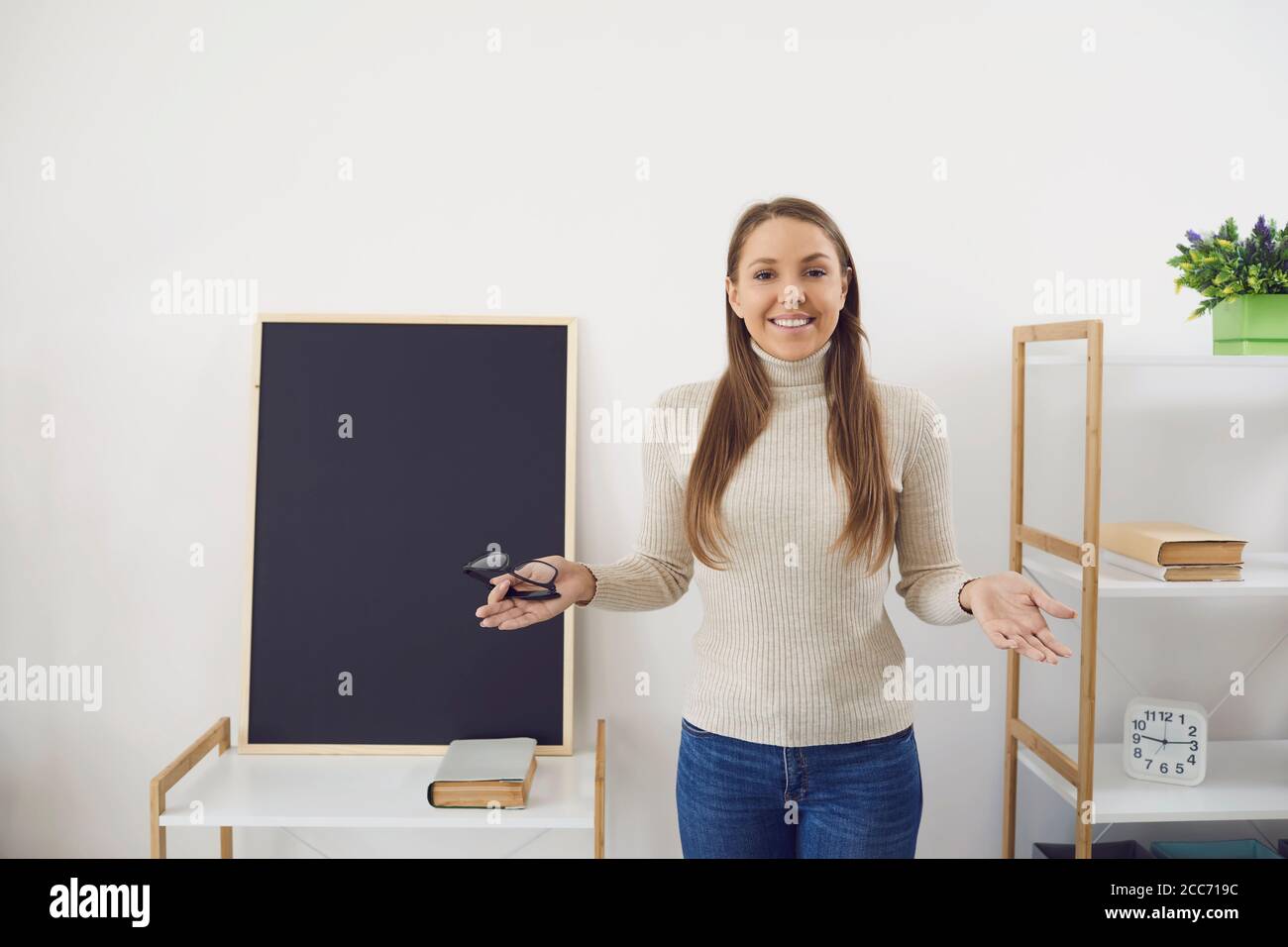 Formation en ligne. Un professeur avec des lunettes souriant sourit dans la vidéo chat vidéo de la leçon d'appel au tableau noir dans la salle de classe. Banque D'Images