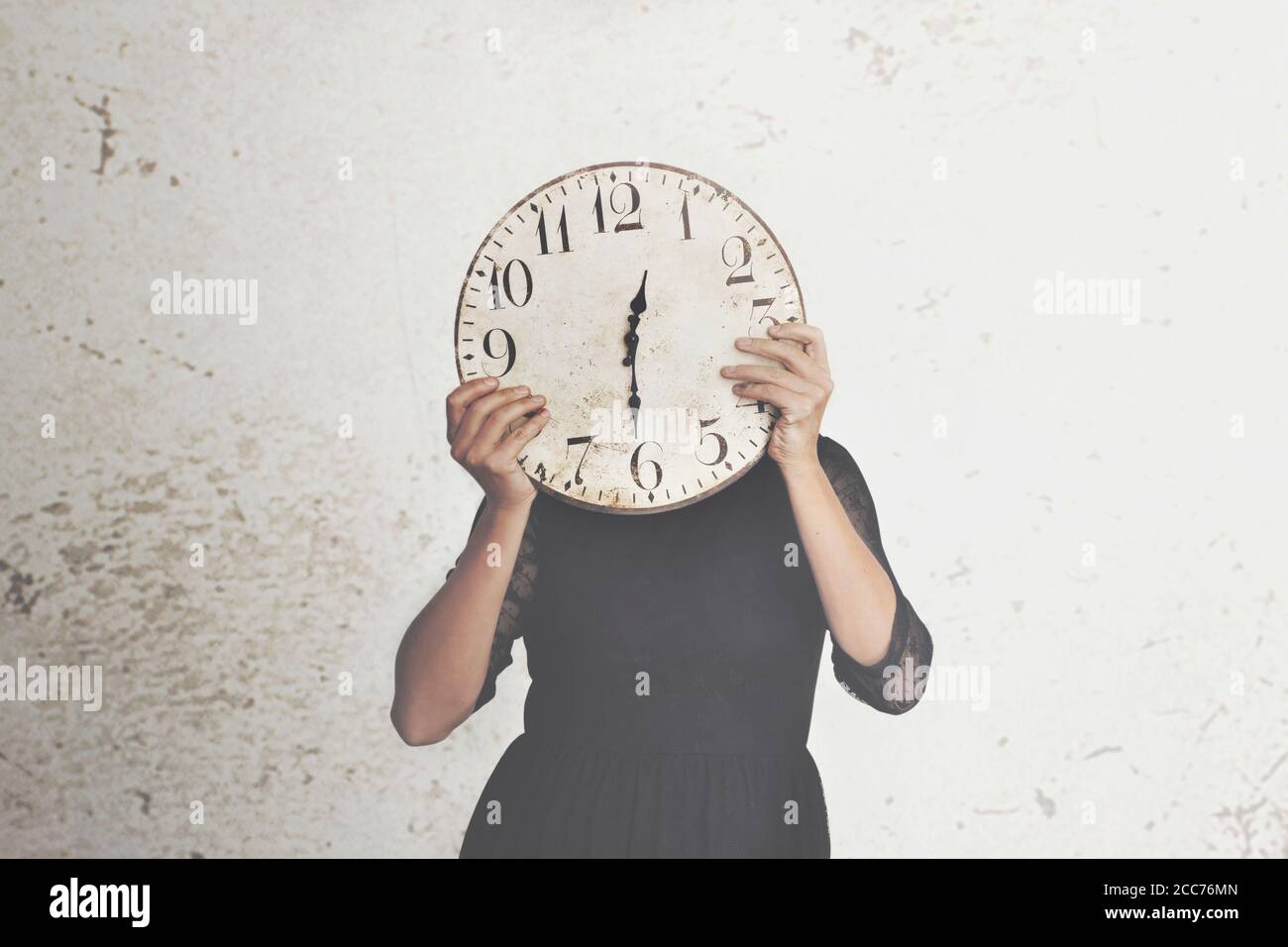 photo surréaliste d'une femme qui se cache derrière une grande horloge Banque D'Images