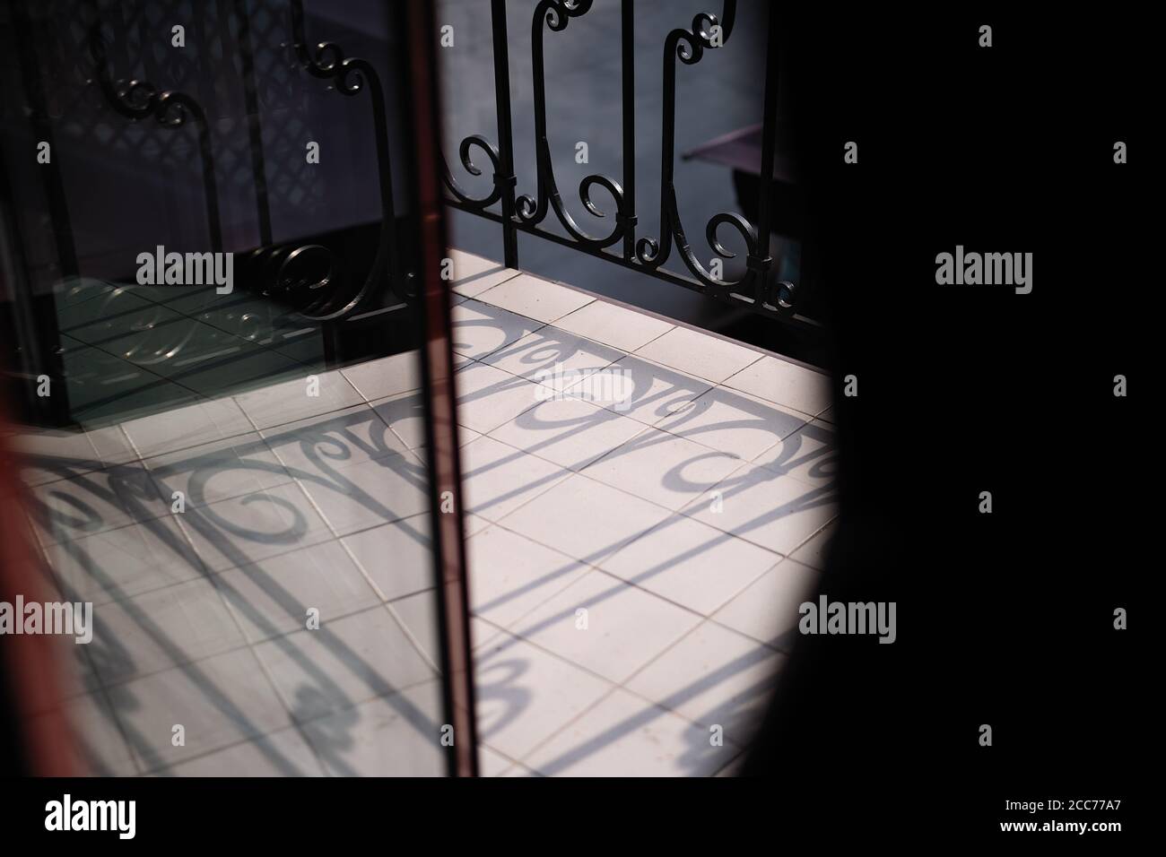 reflet d'un motif orné en verre, ombres sur le sol de la clôture forgée Banque D'Images