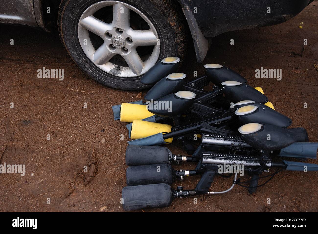 les pistolets de paintball sont au sol près de la roue de la voiture Banque D'Images