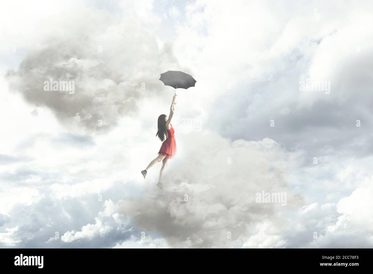 Moment surréaliste d'une femme élégante volant au milieu des nuages accrochés à son parapluie Banque D'Images