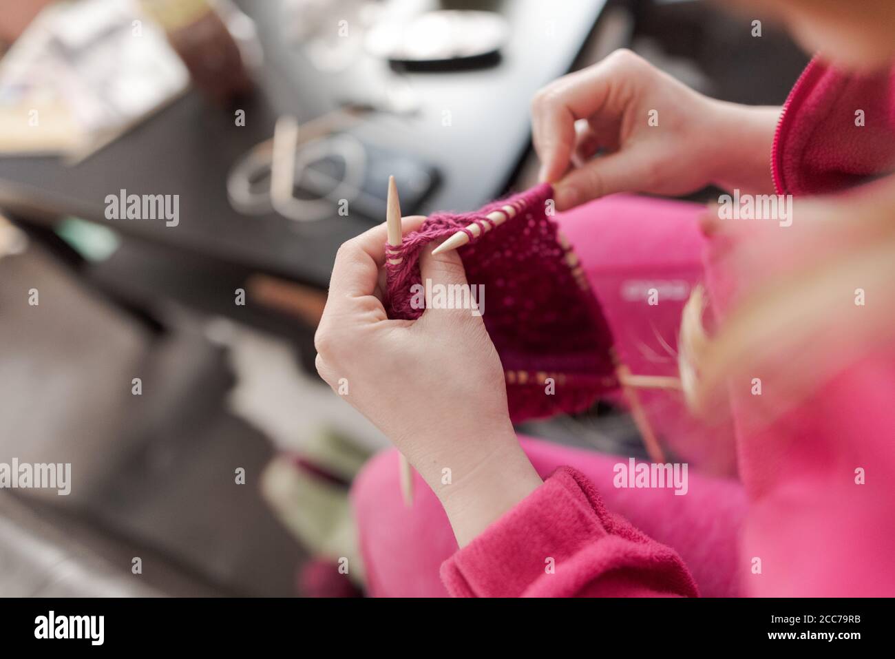 Mains de la jeune femme tricoter des chaussettes à la maison avec du rose laine Banque D'Images