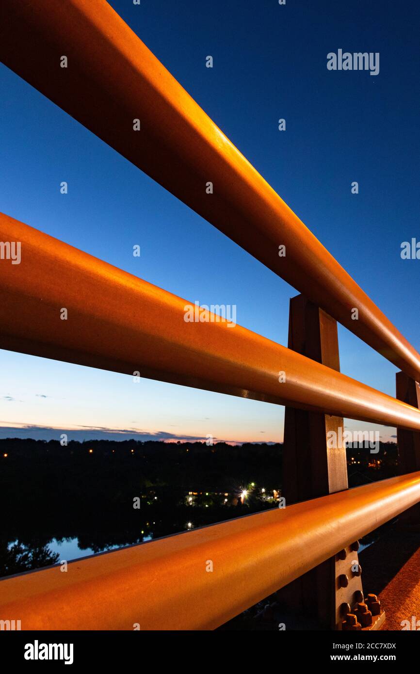 Vue sur Absrat à travers une rambarde métallique robuste ; vue sur le coucher du soleil et les gratte-ciel de banlieue depuis l'arrière de la protection de rail en métal Banque D'Images