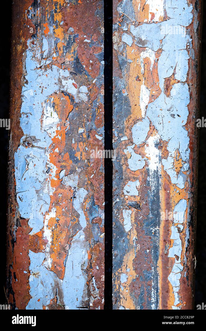 Vue abstraite de la peinture au plomb écaillée sur une surface métallique très rouillée; couleurs bleu, orange et rouge Banque D'Images