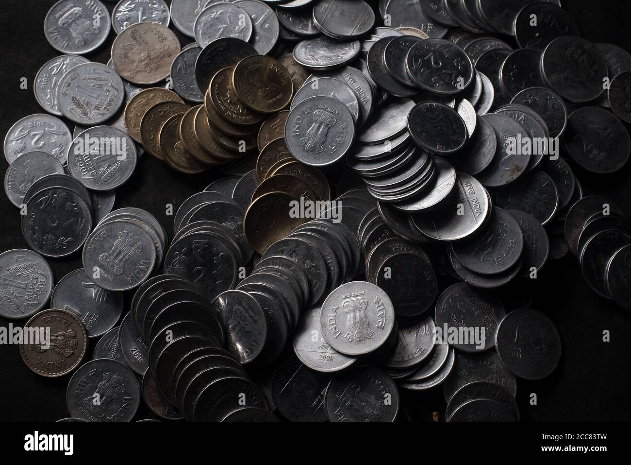 Pile de pièces de monnaie indiennes et cinq roupies note sur un arrière-plan noir Banque D'Images