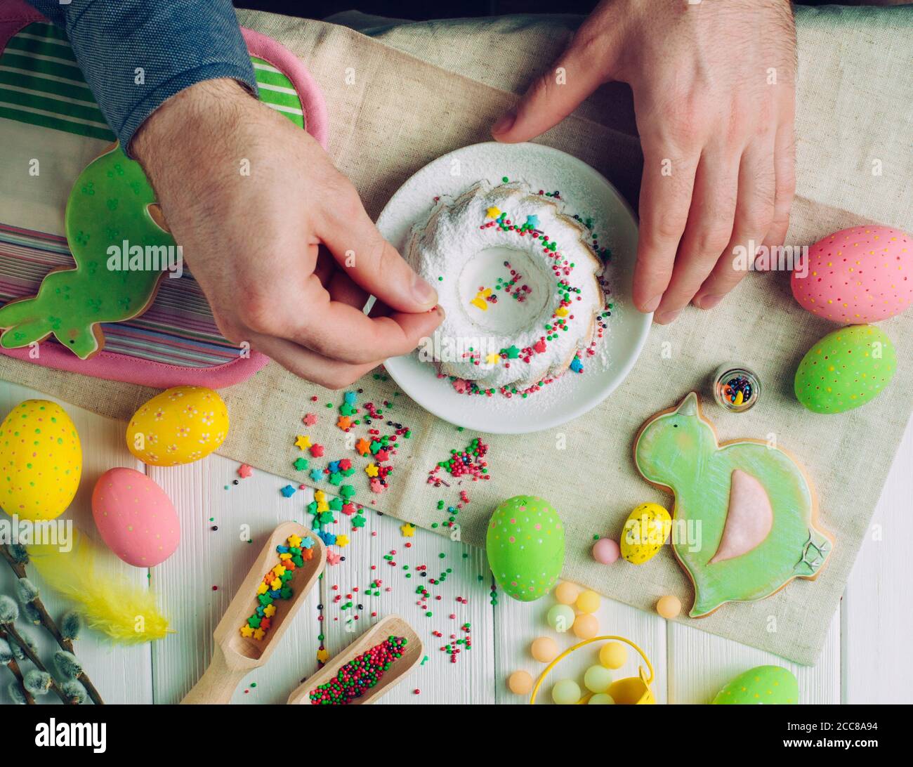 Les mains de l'homme décorent le gâteau traditionnel de Pâques avec des sucreries Banque D'Images