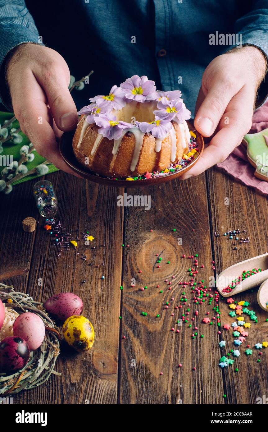 Les mains de l'homme tenant un gâteau traditionnel de Pâques décoré de fleurs Banque D'Images