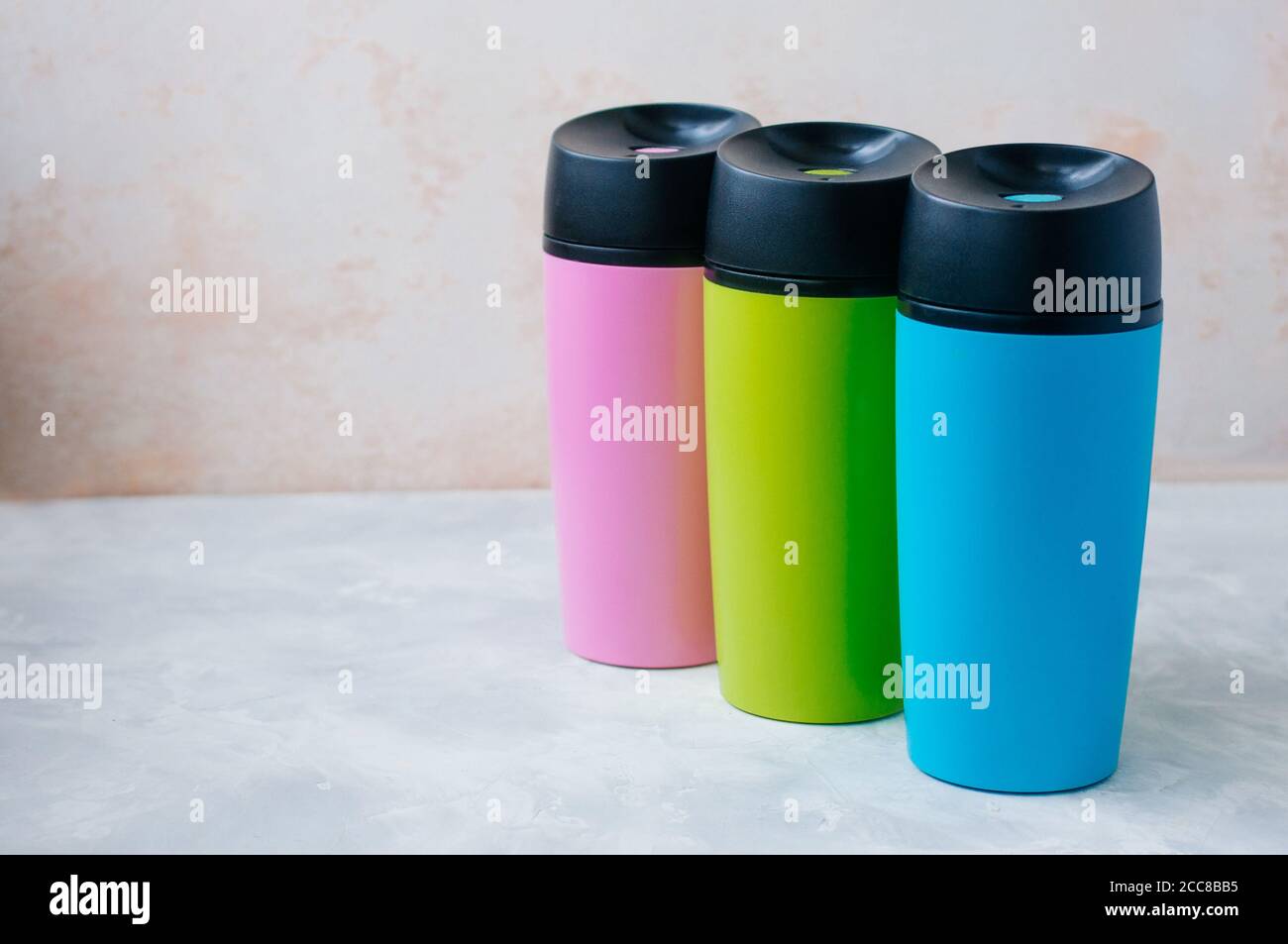 Trois mugs thermos en plastique sur fond gris avec copie espace Banque D'Images