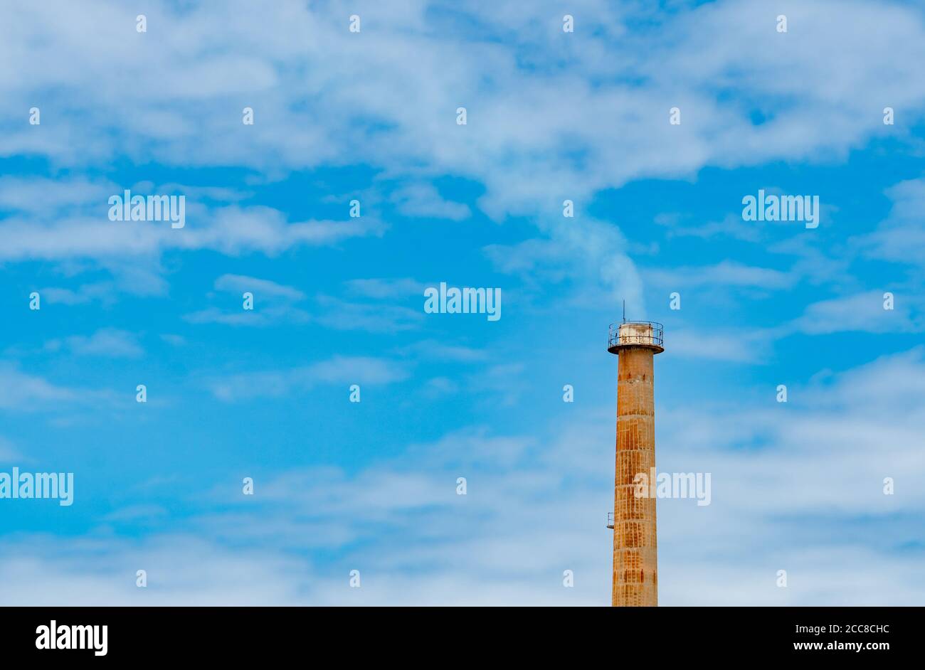Tuyau de fumée rouillé de l'usine contre le ciel bleu et les nuages blancs. Fumée blanche de cheminée de tuyau industriel. Nettoyez l'air autour de l'usine. Environnement Banque D'Images