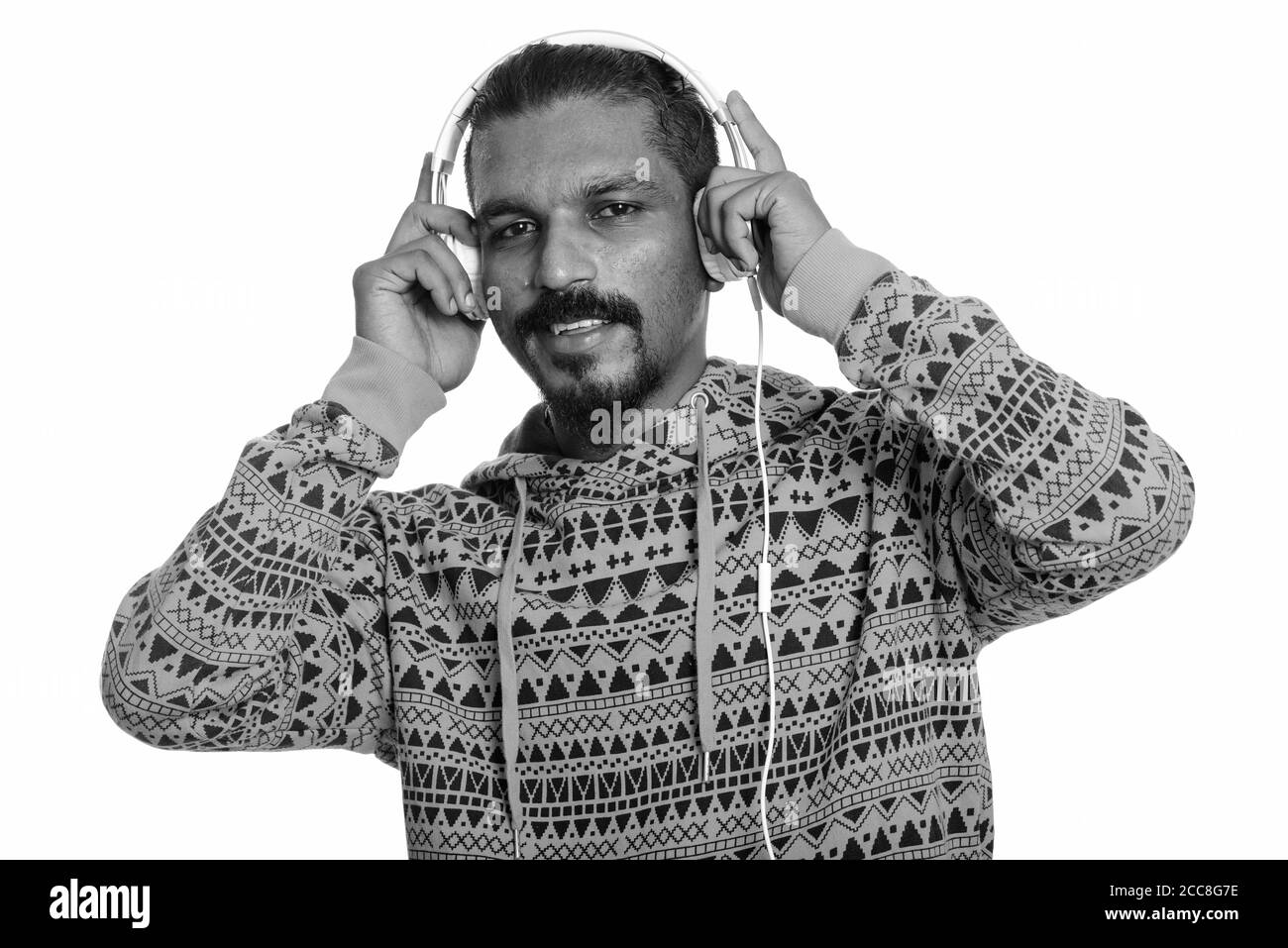 Young happy Indian man smiling tout en écoutant de la musique Banque D'Images