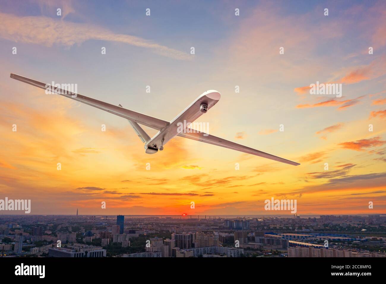 Un drone militaire sans pilote uav volant dans les airs au-dessus du ville au coucher du soleil Banque D'Images