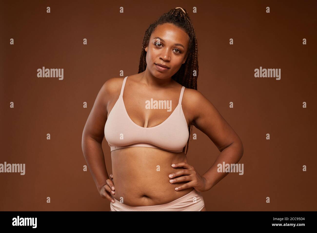 Portrait d'une jeune femme africaine aux formes bosse caméra sur fond marron Banque D'Images