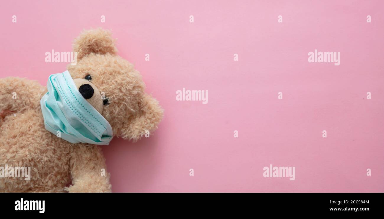 CHIL Kid coronavirus et pollution pm2,5 concept de protection. Τeddy porter un masque de protection sur fond rose, gabarit, bannière Banque D'Images