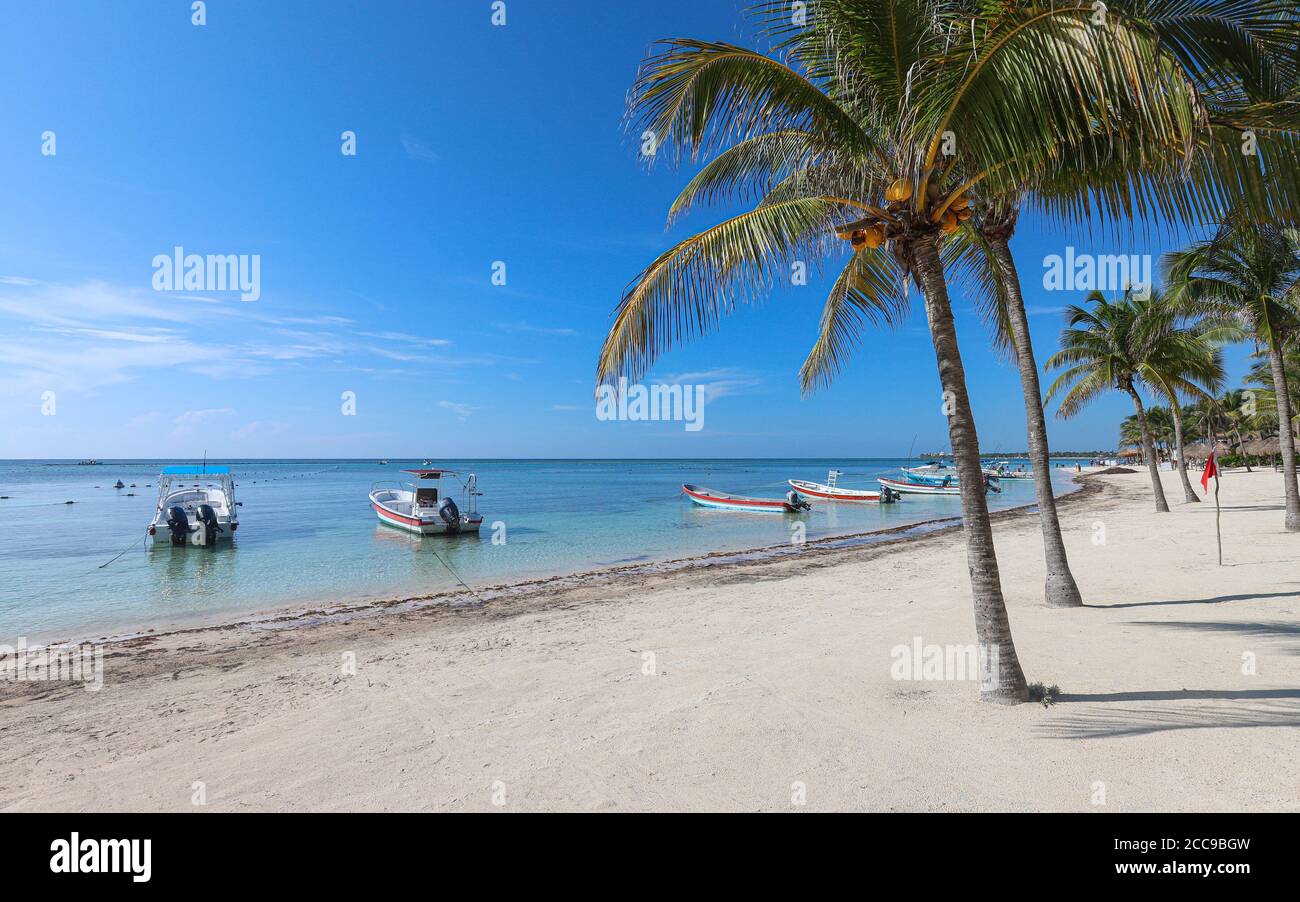 TULUM, QUINTANA ROO, MEXIQUE - 23 juillet 2019 : des bateaux flottent sur les eaux émeraude de la plage d'Akumal, sur la Riviera Maya du Mexique. Banque D'Images TULUM, QUINTANA ROO, MEXIQUE - 23 juillet 2019 : des bateaux flottent sur les eaux émeraude de la plage d'Akumal, sur la Riviera Maya du Mexique. Banque D'Images
