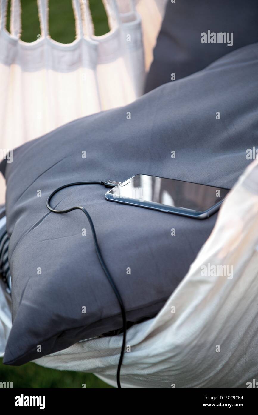 Un téléphone plus intelligent se recharge sur l'oreiller dans un nid suspendu Banque D'Images
