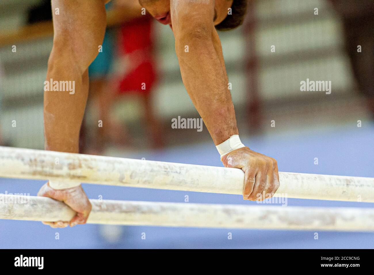 Gymnaste de l'équipe nationale française sur les barres parallèles, un des appareils de gymnastique artistique des hommes. Craie pour garder les mains au sec Banque D'Images