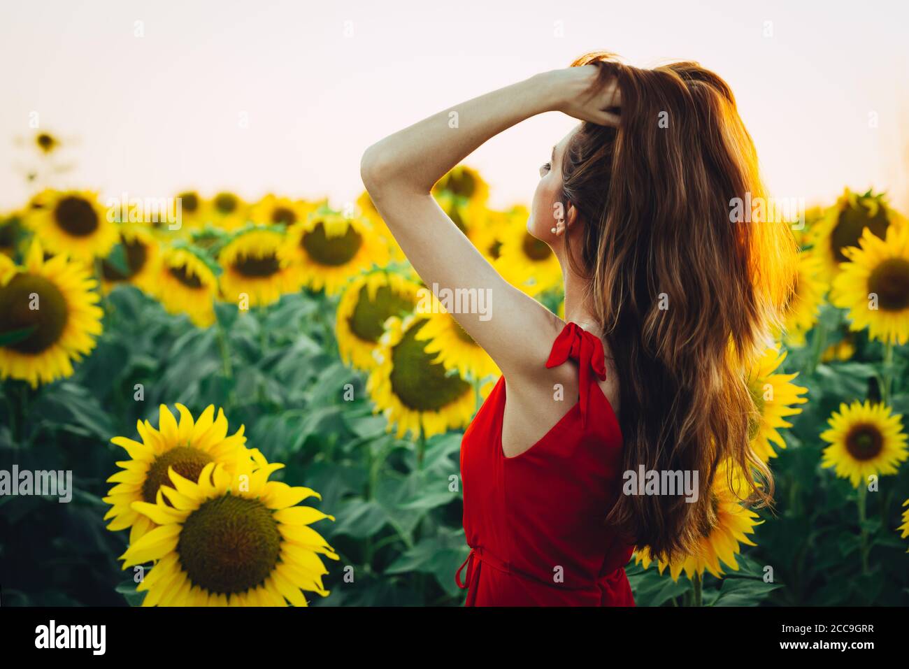 jeune femme dans le parc avec les bras étirés et jouant avec les cheveux Banque D'Images