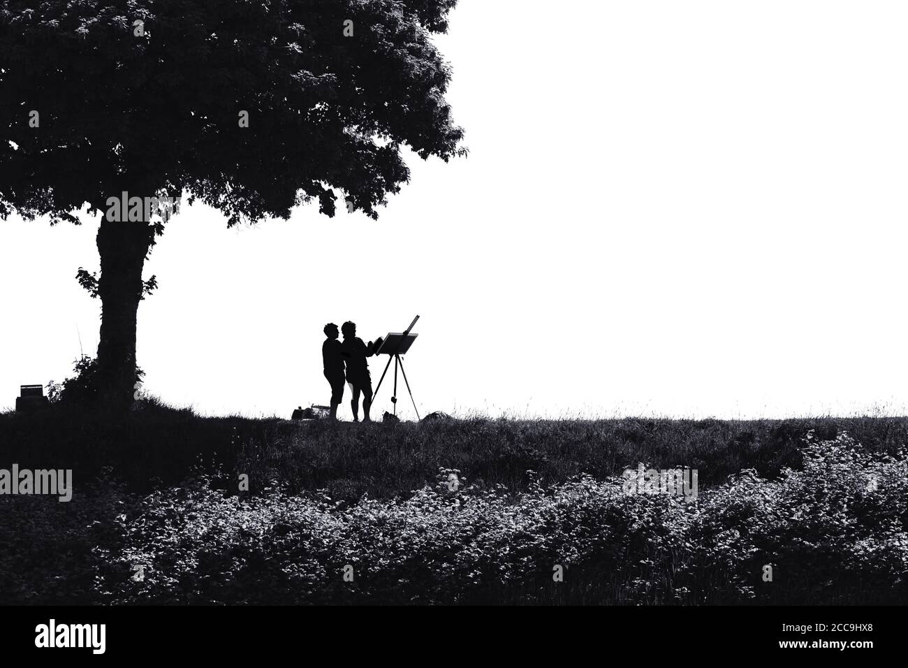 Noir et blanc, image presque silhouettée de deux peintres paysagistes au-dessous d'un arbre sur une digue en France Banque D'Images
