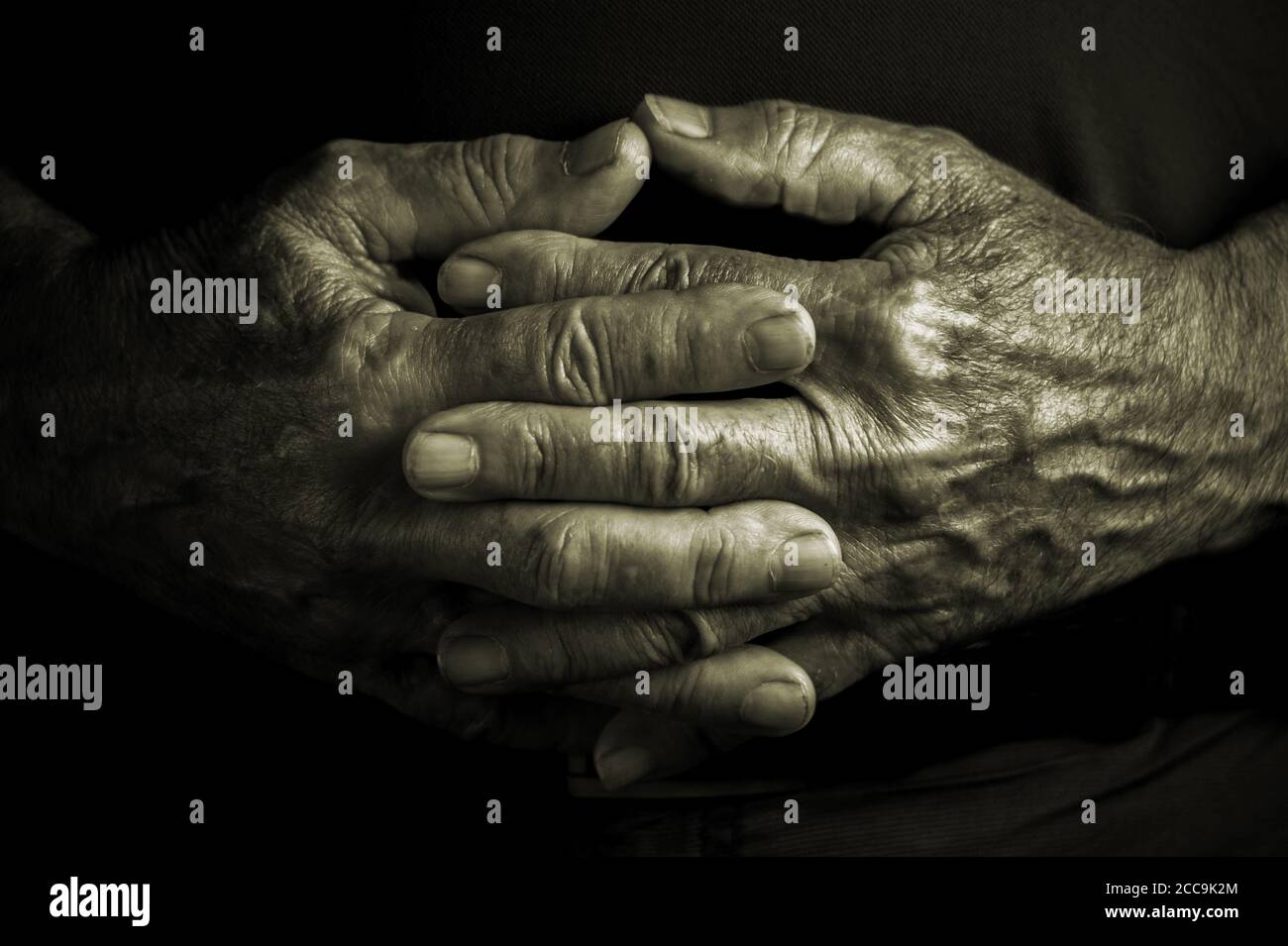 Adulte âgé âgé âgé avec des mains froissées croisées au repos e position de détente - fond noir Banque D'Images