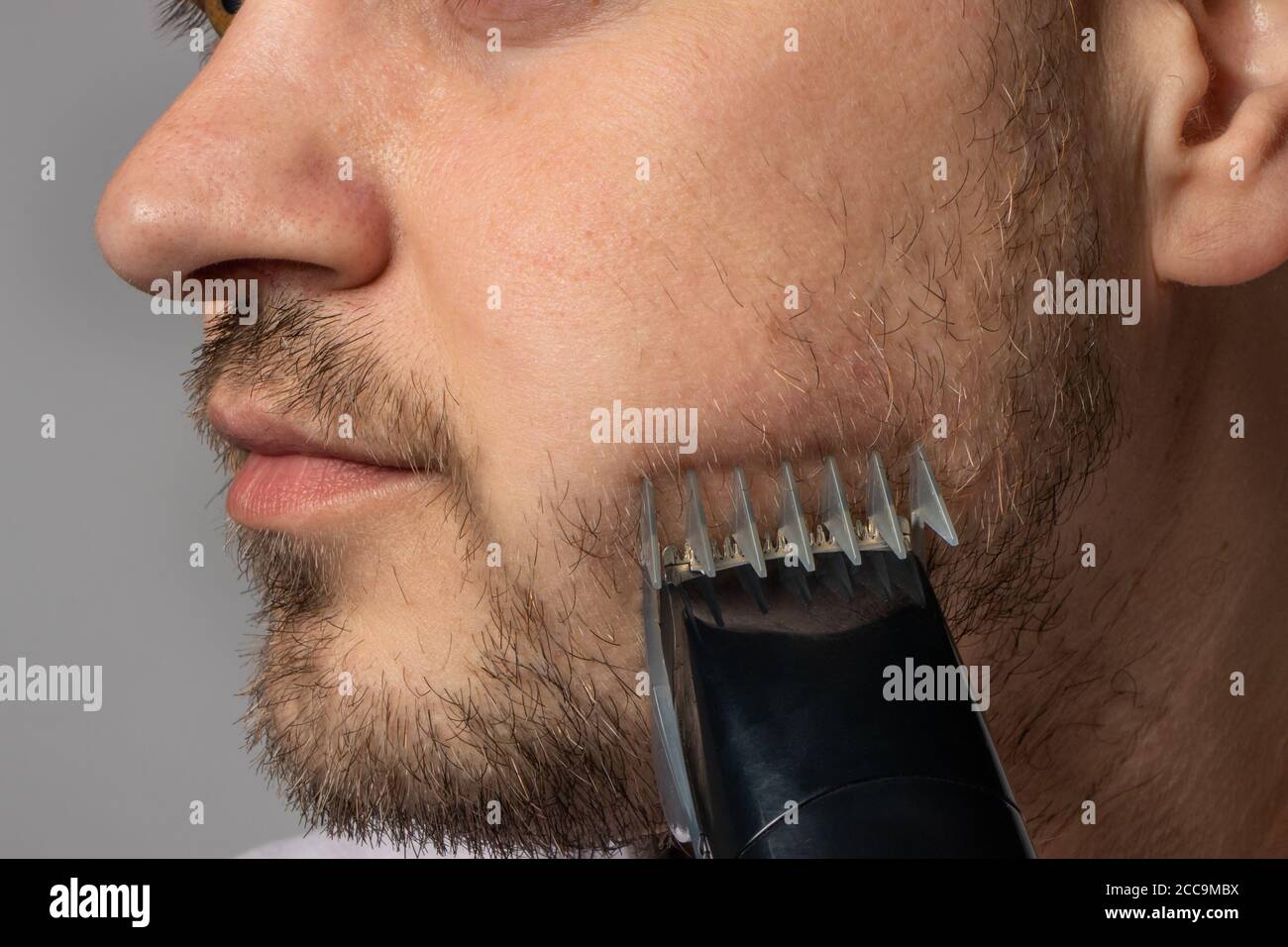 Un homme rasages sa barbe avec un rasoir de tondeuse. La barbe à modeler, le  style masculin, les soins des cheveux du visage, les routines matinales  dans la salle de bains Photo