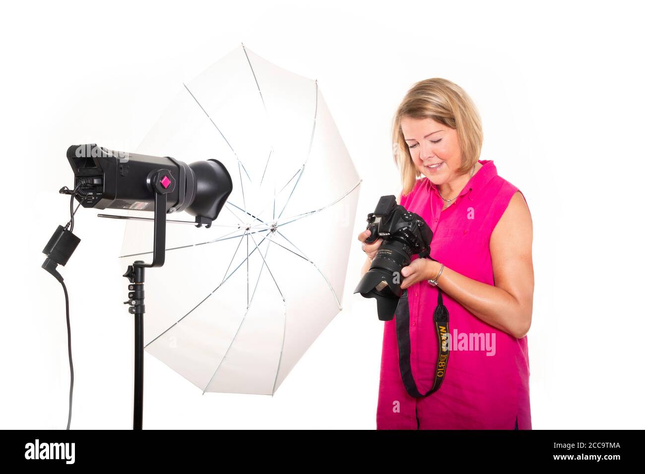 Portrait horizontal d'un photographe qui vérifie les photos à l'arrière d'un appareil photo numérique tout en travaillant en studio. Banque D'Images