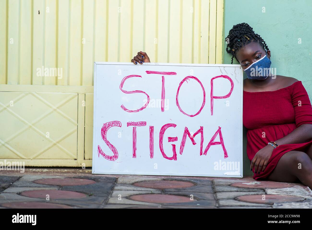 Jeune femme noire avec un masque médical tenant une planche Avec le texte « Stop stigmate » Banque D'Images