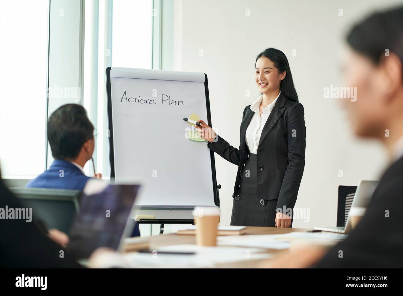 jeune femme d'affaires asiatique présentant des plans d'action lors d'une réunion avec collègues Banque D'Images jeune femme d'affaires asiatique présentant des plans d'action lors d'une réunion avec collègues Banque D'Images