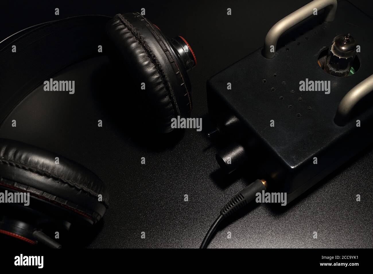 Les écouteurs grand format sont placés avec un préamplificateur à tube sur un fond noir. Banque D'Images