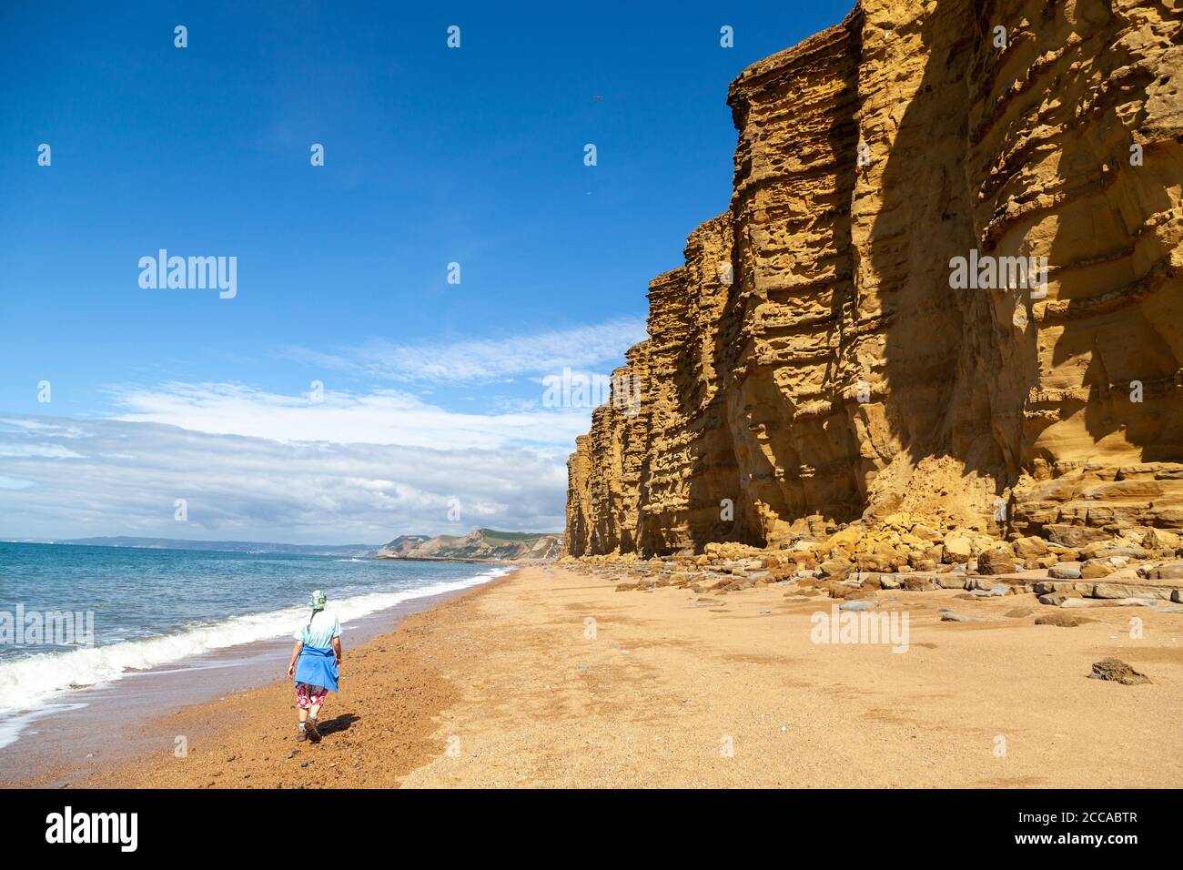 Un marcheur marchant sous les falaises spectaculaires près de Burton Freshwater sur la côte jurassique, Dorset, Angleterre, Royaume-Uni Banque D'Images