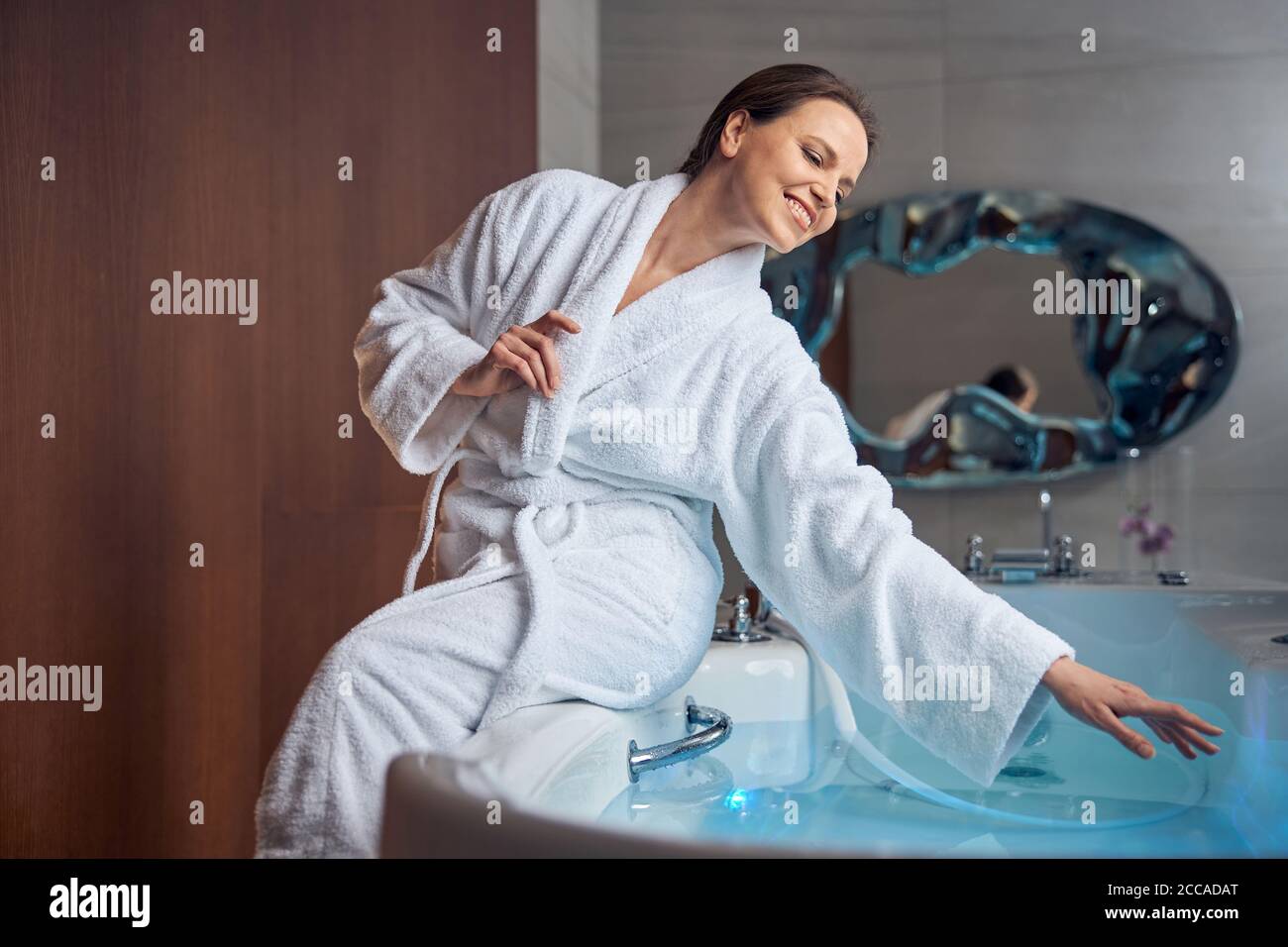 Une jolie dame très animée assise dans une salle de bains Banque D'Images