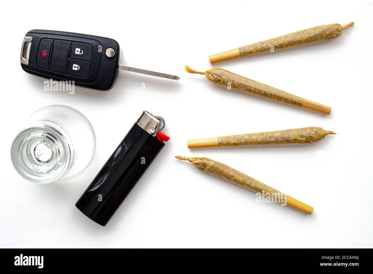 Le cannabis joint des cigarettes avec clé de voiture, un verre de pousse et un briquet sur fond blanc. Concept de conduite élevée. La conduite avec facultés affaiblies par la drogue est dangereuse A. Banque D'Images