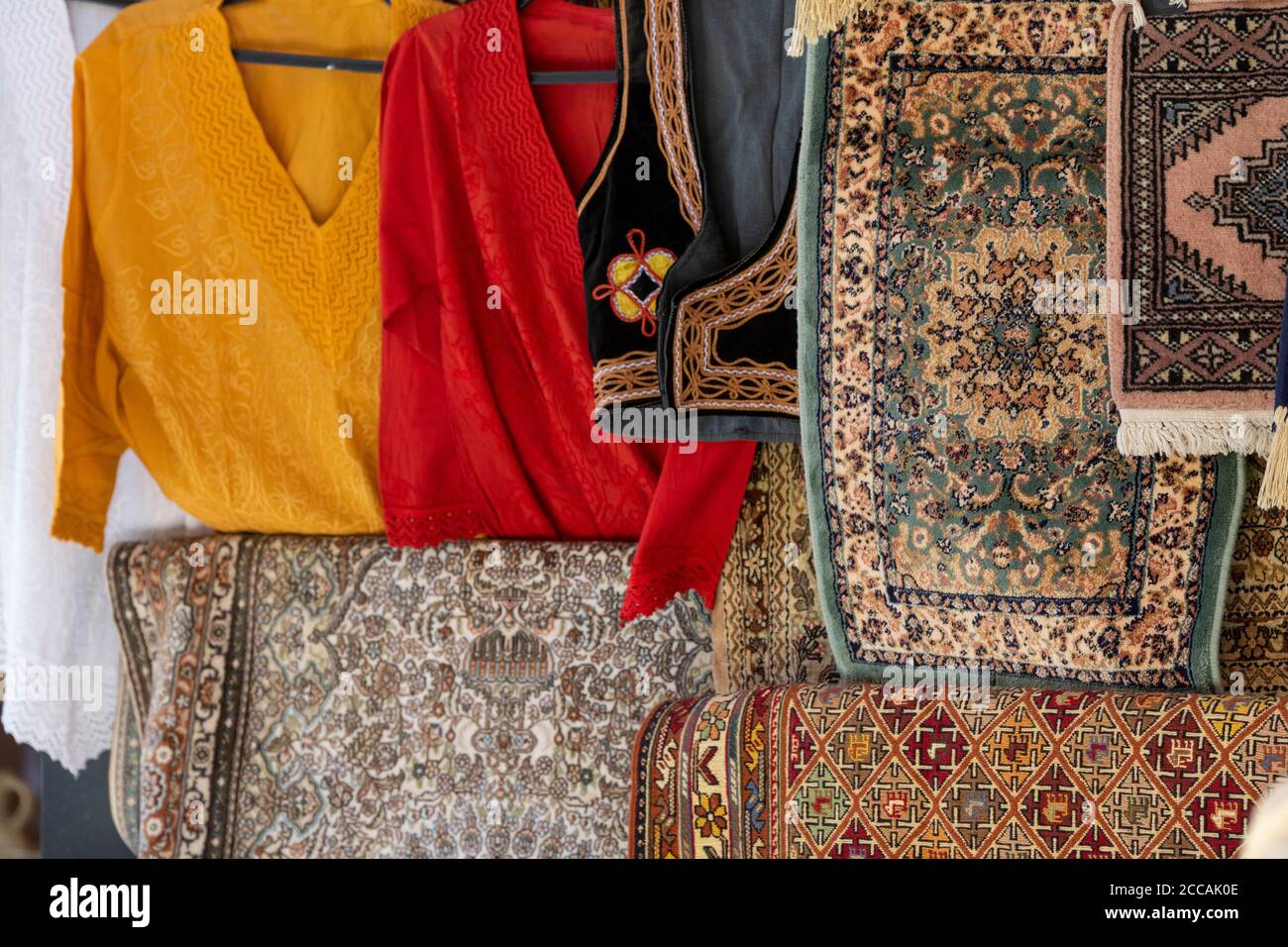 Israël, Jérusalem. Vieille ville, via Dolorosa. Présentation typique du fournisseur avec tapis de prière et chandails traditionnels. Banque D'Images