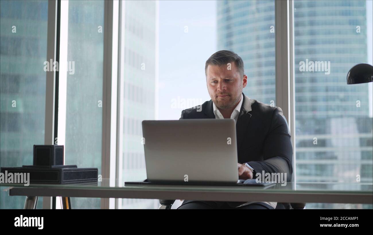 Un homme d'affaires travaille derrière un ordinateur portable en hêtre dans son bureau. Un homme d'affaires heureux qui navigue sur le Web depuis son ordinateur portable au bureau Banque D'Images