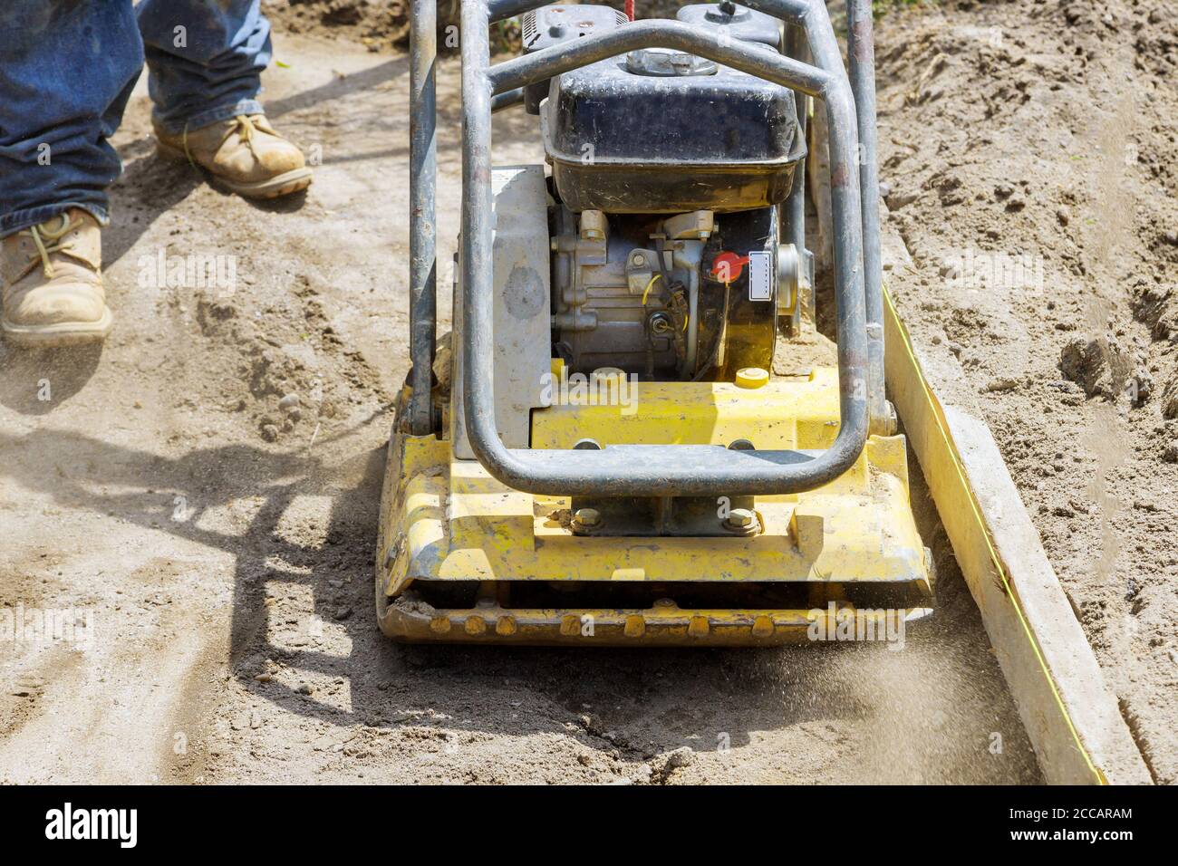 L'employé du compacteur à plaque vibrante utilise le compacteur pour le sol sur le chantier en construction Banque D'Images