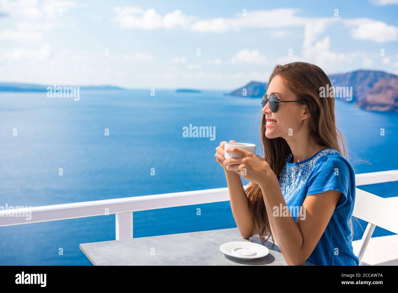 Bonne femme asiatique buvant un café en vacances d'été dans un luxueux café de l'hôtel avec une vue imprenable sur Oia, Santorini. Voyage en Europe Banque D'Images