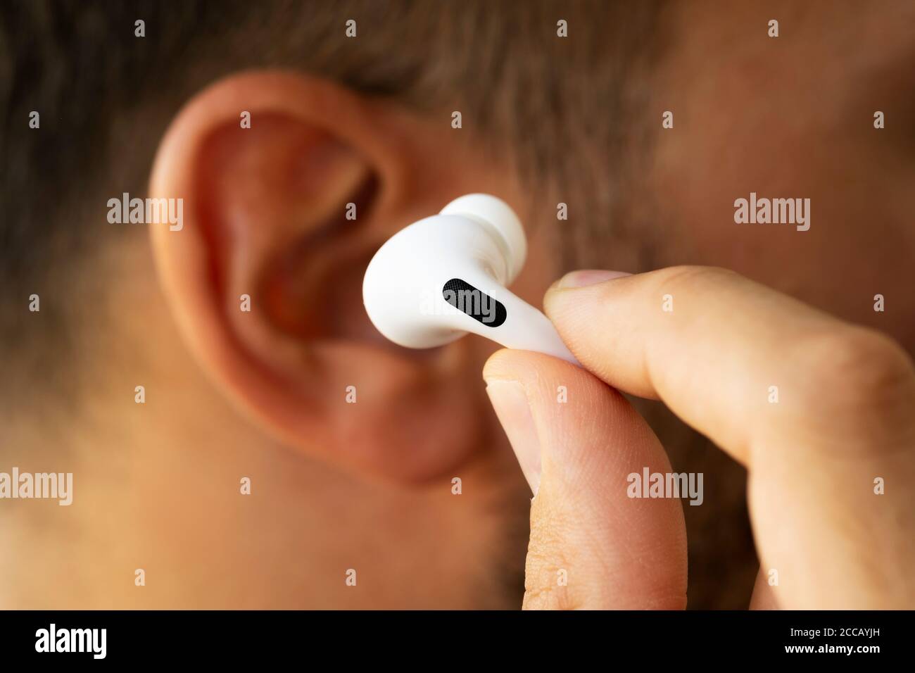 Izmir, Turquie - 7 août 2020 : gros plan d'Airpodes aux pommes blancs sur l'oreille d'un homme. Banque D'Images