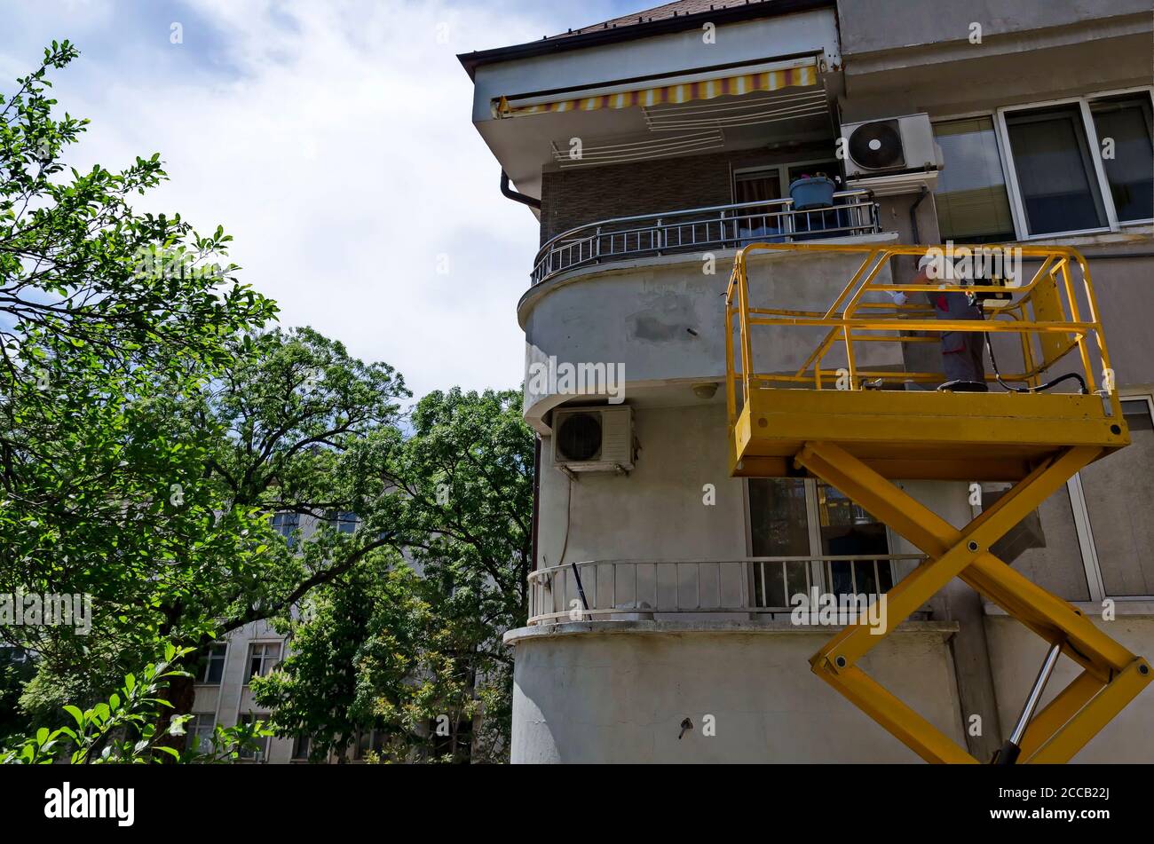 Un peintre rafraîchit le plâtre d'une maison à l'extérieur avec une plate-forme élévatrice, Sofia, Bulgarie Banque D'Images