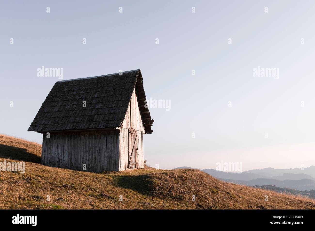 Pittoresque prairie d'automne avec ancienne maison en bois et ciel clair dans les montagnes Carpates, Ukraine. Photographie de paysage Banque D'Images