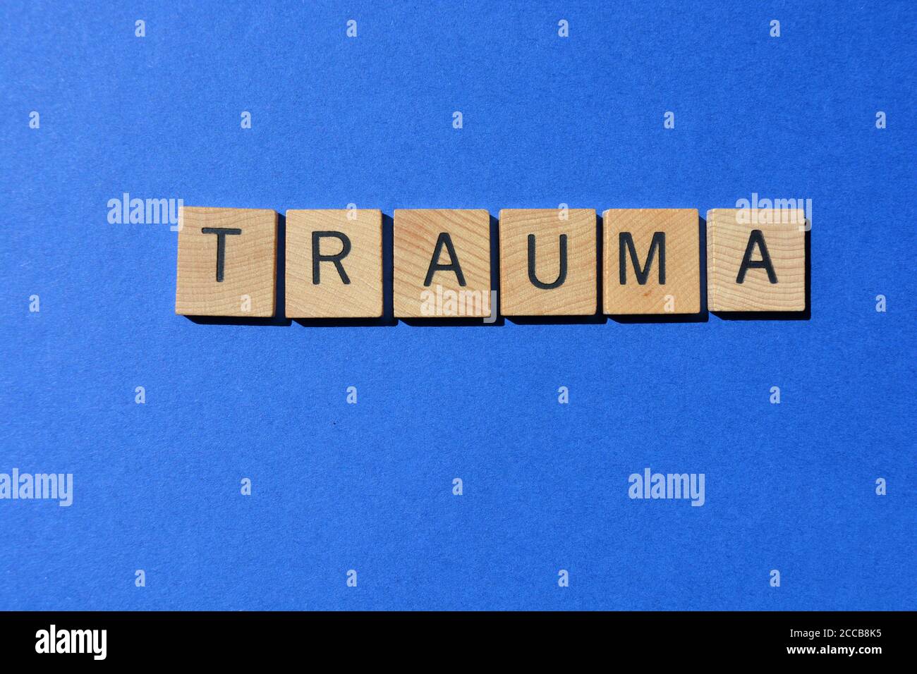 Trauma, mot en lettres de l'alphabet de bois isolées sur fond bleu Banque D'Images