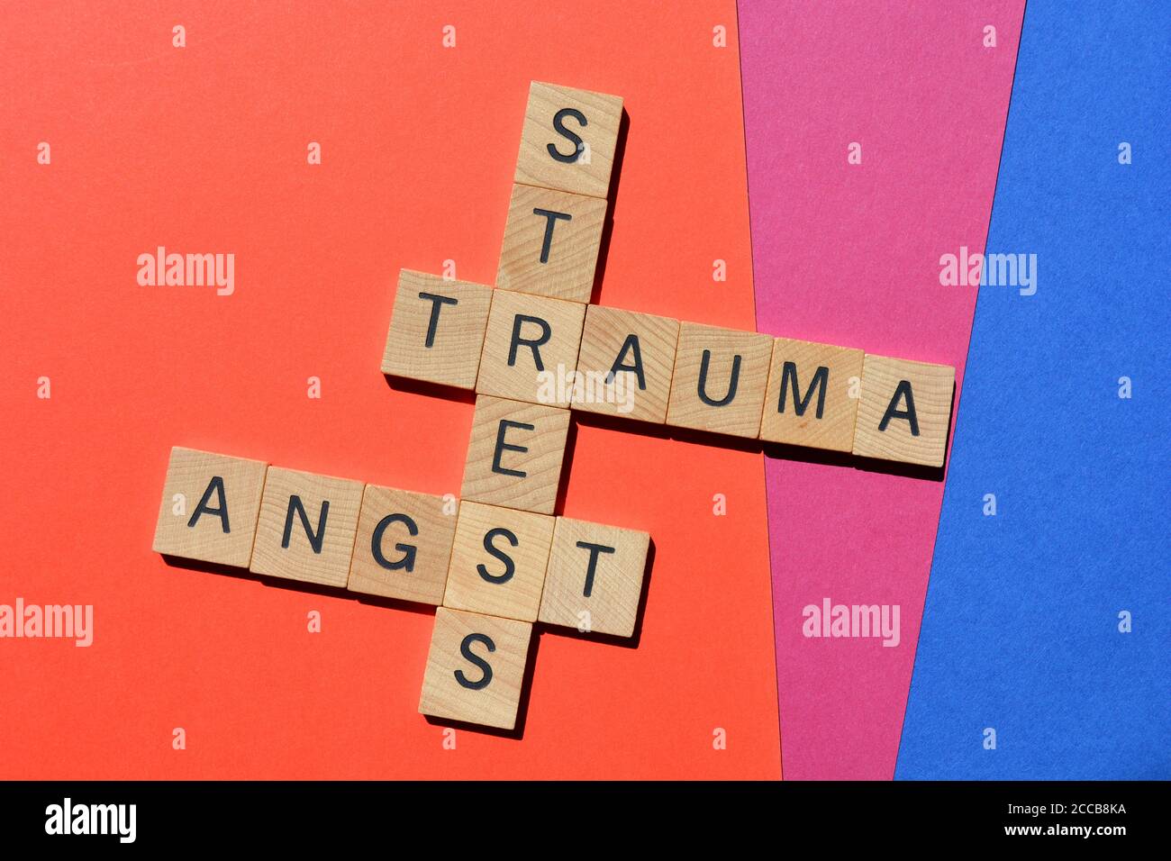 Stress, Trauma, Angst, mots en lettres de l'alphabet en bois sous forme de mots croisés sur fond coloré. Banque D'Images